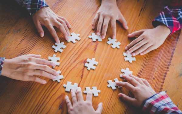 Hands of diverse people assembling jigsaw puzzle, Youth team put pieces together searching for right match, help support in teamwork to find common solution concept, top close up view