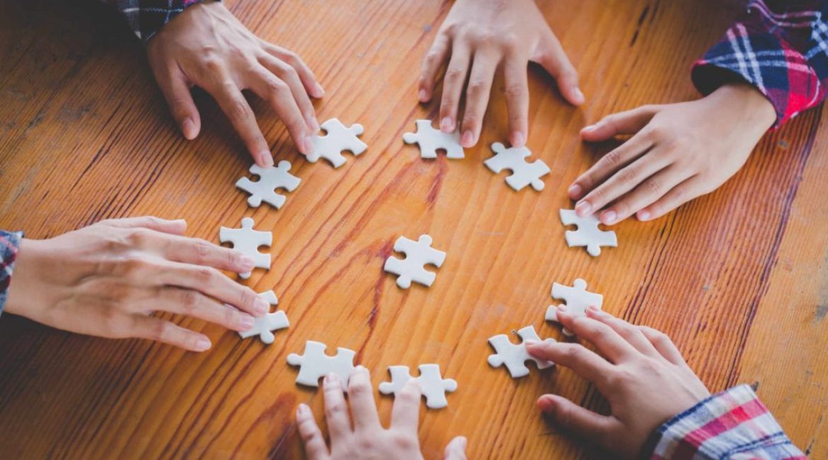 Hands of diverse people assembling jigsaw puzzle, Youth team put pieces together searching for right match, help support in teamwork to find common solution concept, top close up view