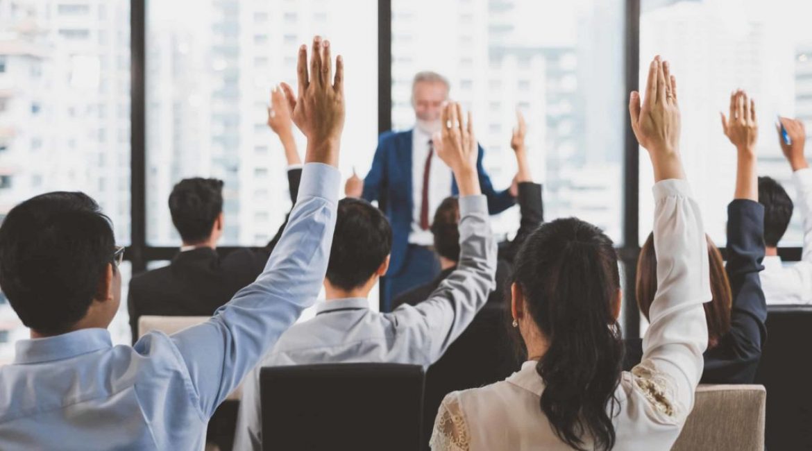 Group of business people raise hands up to ask question and answer to speaker in the meeting room seminar