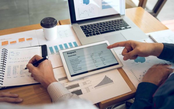 Business partnership coworkers using a tablet to analysis graph company financial budget report and cost work progress and planning for future in office room.