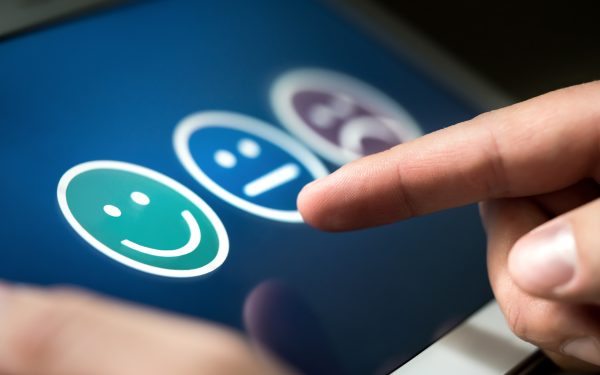 Survey, poll or questionnaire for user experience or customer satisfaction research. Quality control and feedback concept. Man choosing his opinion with smiley faces on touch screen.